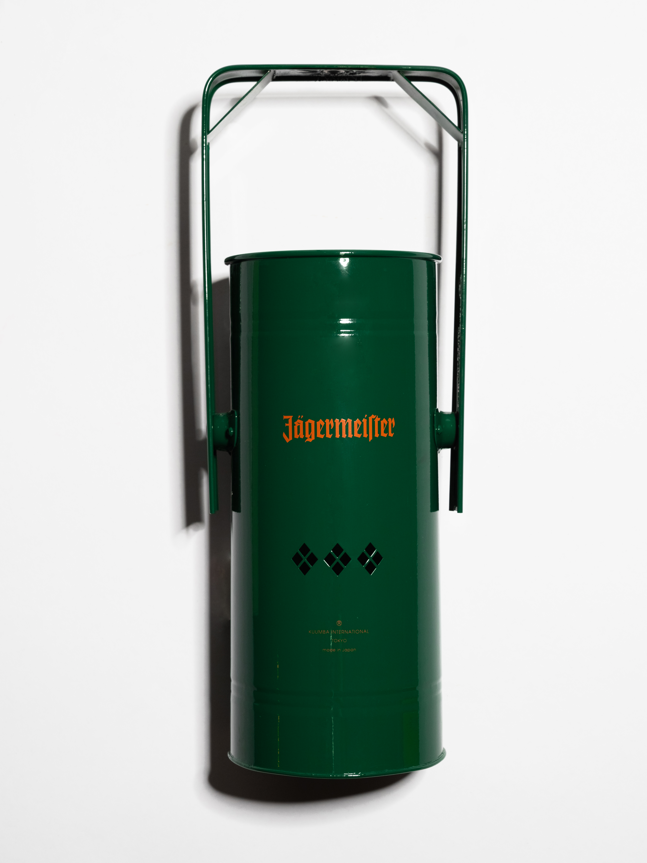 Brûle-encens en métal vert avec poignée et logo Jägermeister orange sur fond blanc