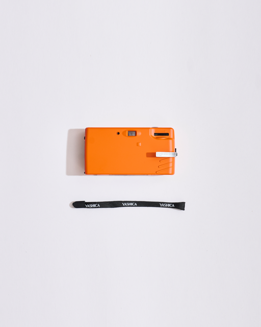 Appareil photo orange avec une sangle sur fond blanc