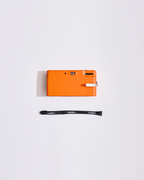 Appareil photo orange avec une sangle sur fond blanc