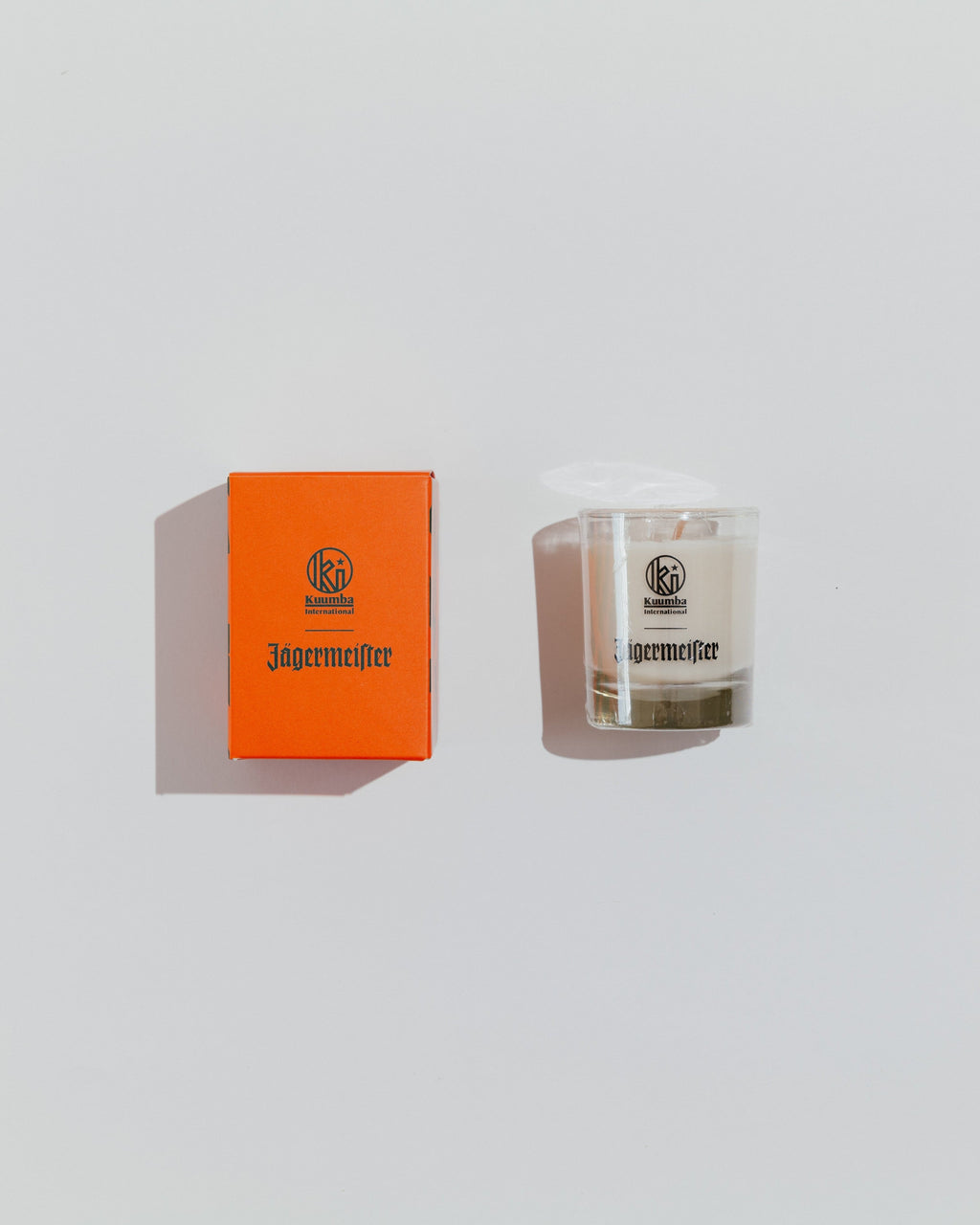 Bougie Jägermeister et boîte orange sur fond gris clair