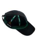 Casquette noire avec intérieur vert et logo de marque Jägermeister visible.