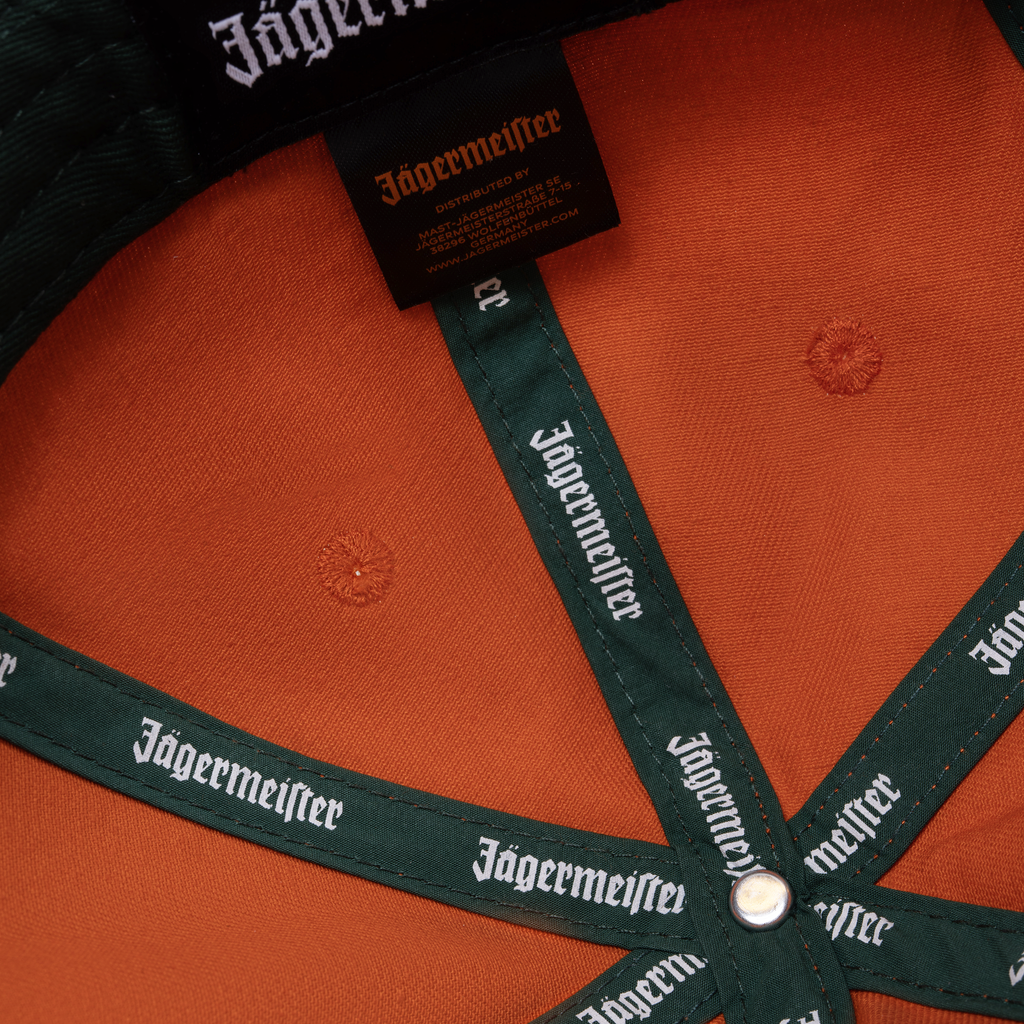 Casquette orange Jägermeister Racing avec branding Jägermeister sur la sangle et l’étiquette.