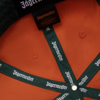 Casquette orange Jägermeister Racing avec branding Jägermeister sur la sangle et l’étiquette.