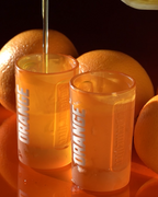 Deux verres à shot Jägermeister orange avec des oranges en arrière-plan.