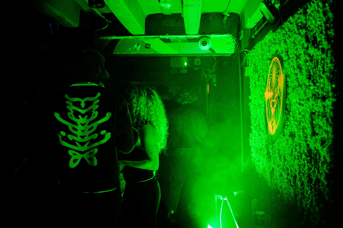 Guests gathered in a green-lit venue beside a moss wall featuring an illuminated Jägermeister stag logo.